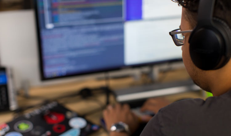 A technical professional works at a desk with computer monitors